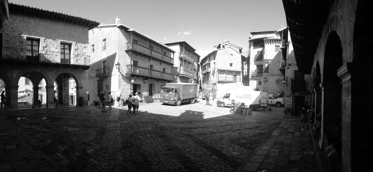 PEOPLE WALKING ON STREET AMIDST BUILDINGS IN CITY