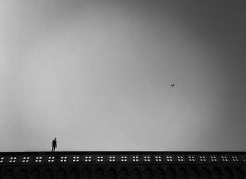 Low angle view of silhouette people on bridge against clear sky