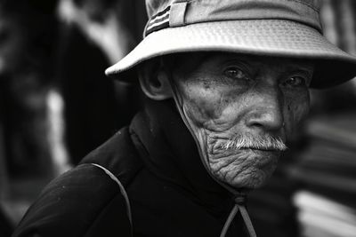 Close-up portrait of senior man wearing hat sitting outdoors