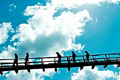 Low angle view of silhouette people against blue sky