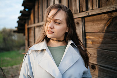 Girl with long hair in a grey trench coat outdoors in spring