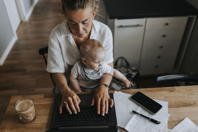 Multitasking mother taking care of baby and working from home