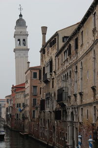 Buildings by canal against sky