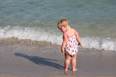 Rear view full length of girl standing on shore at beach