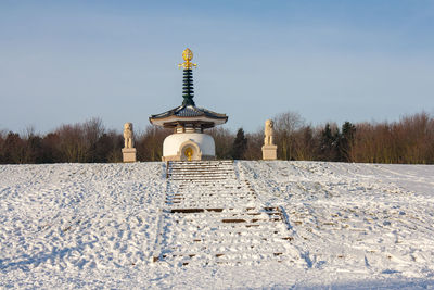 Cross on snow covered field against sky