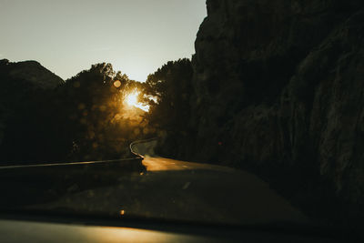 Road amidst trees against sky during sunset