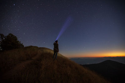 Man standing on field against sky at night