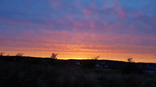 Scenic view of silhouette field against sky during sunset