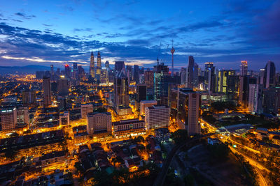 Aerial view of city lit up against cloudy sky