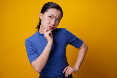 Portrait of beautiful young woman against yellow background