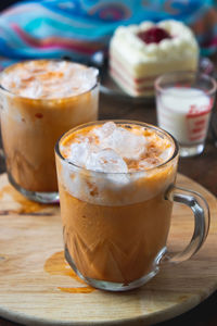 Close-up of iced coffee in cups on cutting board over table