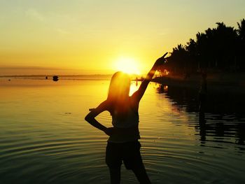 Silhouette woman standing at beach during sunset