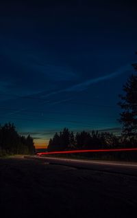 Light trails on road against sky at night