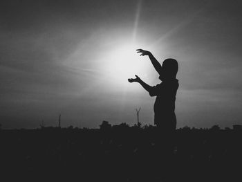 Silhouette man standing on field against sky during sunset