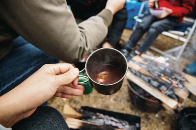 Cropped hand holding coffee at campsite