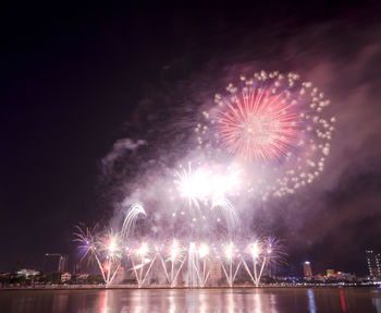 Firework display over river against sky