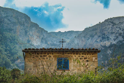 Old building on mountain against cloudy sky