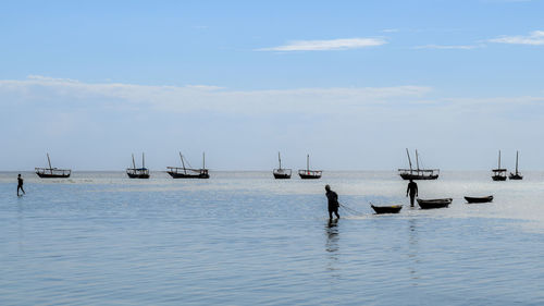 Silhouette fishermen in sea against sky