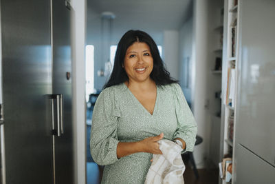 Portrait of smiling woman doing housework in kitchen