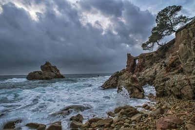 Rock formation on beach against sky