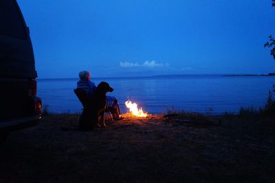 Men sitting on beach against sky