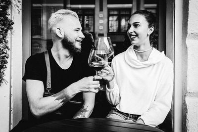 People sitting in front of a man drinking glass