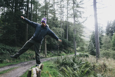 Full length of mid adult man balancing on log in forest