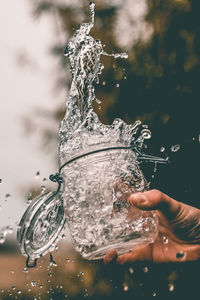 Close-up of hand splashing water through jar