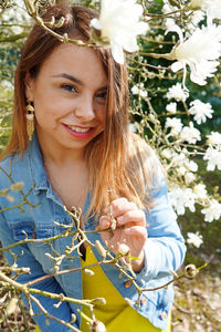 Portrait of smiling woman standing by plant