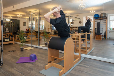 Male fitness pilates trainer shows exercises on special simulators. pilates stretch tables