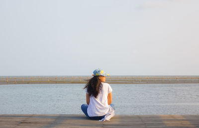 Woman sitting on beach against clear sky