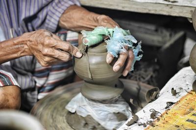 Midsection of man making earthenware on pottery wheel