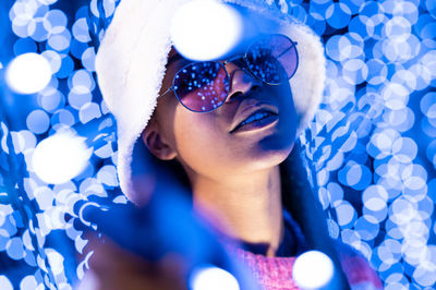 Joyful woman of color with a white beanie braided hairstyle and pink glasses enjoying the christmas 