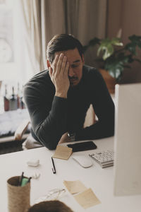 Tired businessman leaning at desk while sitting in office