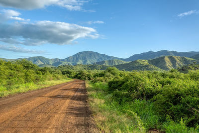 Dirt road along landscape against sky