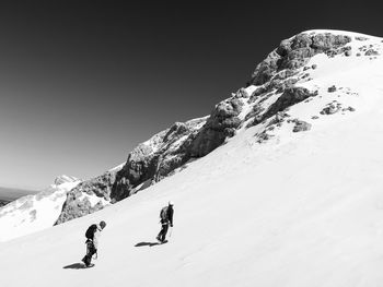 People skiing on snowcapped mountain against sky