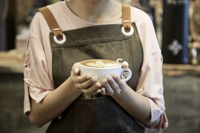 Midsection of man holding coffee cup