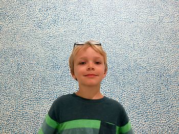 Portrait of smiling boy standing against patterned wall