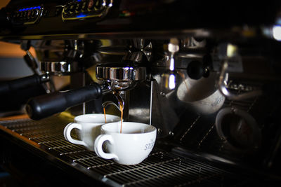 Close-up of machinery pouring coffee in cup at cafe