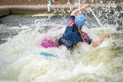 Gb canoe slalom athlete in c1w class in white water action. paddling away surrounded by splashes.