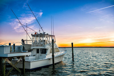 Sailboat moored on sea against sky during sunset