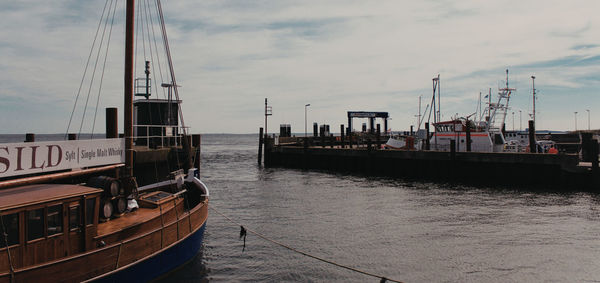 Sailboats moored in sea against sky