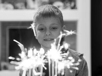 Close-up of cute boy looking at lit candles in home