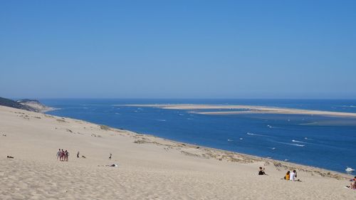 People on beach against clear sky