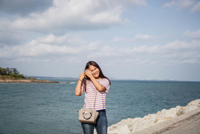 Woman standing by sea against sky