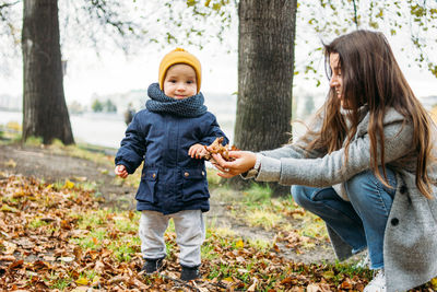 Mother playing with toddler son in park during winter