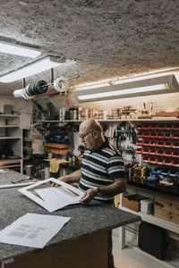 Senior craftsman with frame standing at workbench