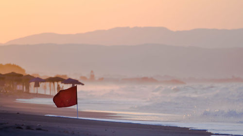 Red flag at beach during sunset