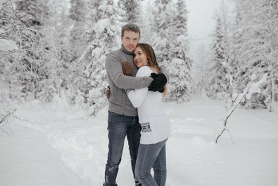 Young hipster couple hugs each other in a winter park.