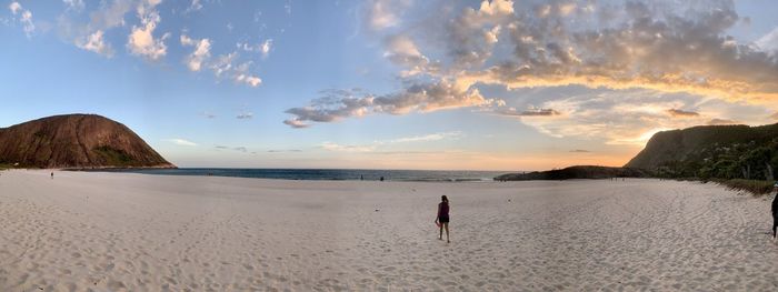 Rear view of man on beach against sky during sunset